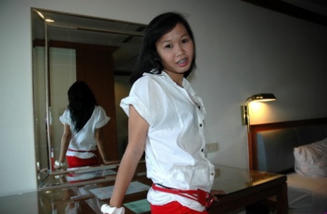 Young looking Asian girl strips naked in a hotel room for a sex tourist