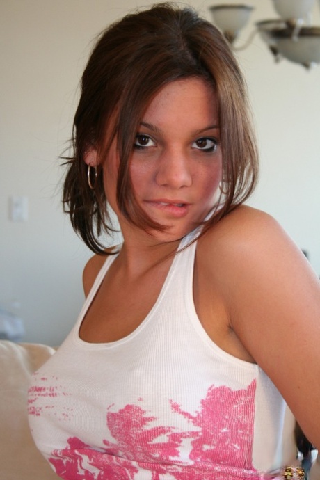 Young solo girl exposes her firm breasts as she goes topless on the sofa