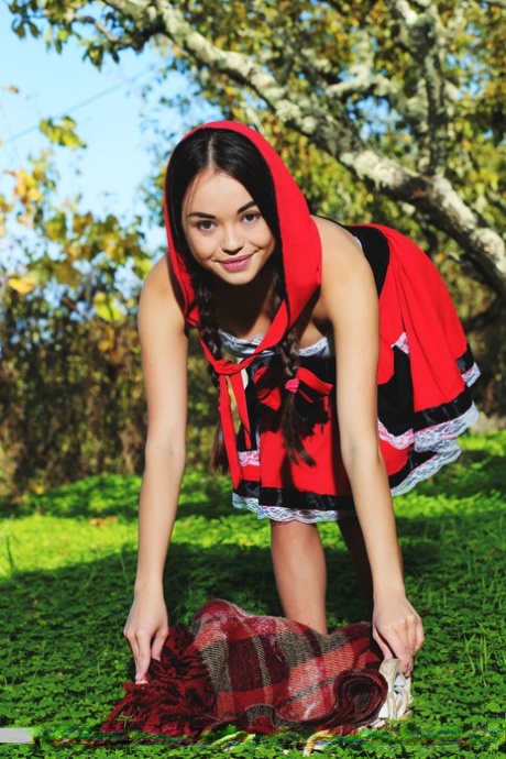 Cute little Li Moon in pigtails on her knees outdoors to show her bald pussy