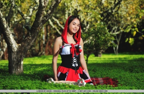 Cute little Li Moon in pigtails on her knees outdoors to show her bald pussy