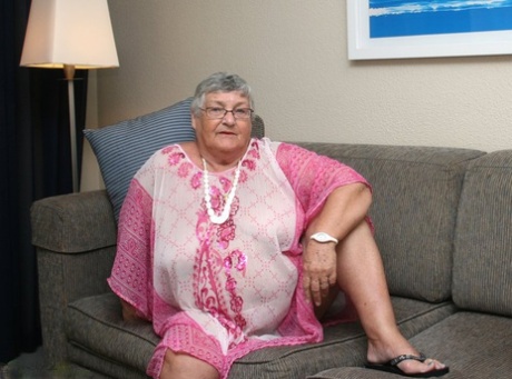Horny Grandma Libby strips and spreads her old shaved pussy on the sofa