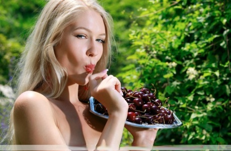 Gorgeous blonde teen Xana D poses nude with a plate of cherries