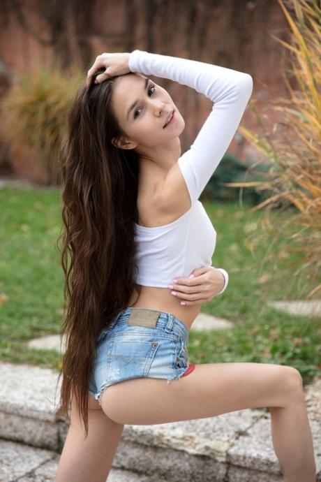 Long legged teen Leona Mia showcases her bald pussy on concrete steps
