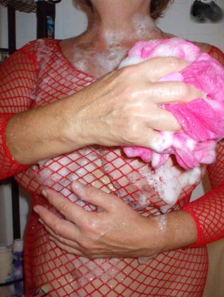 Older amateur Busty Bliss soaps up her boobs in a mesh dress