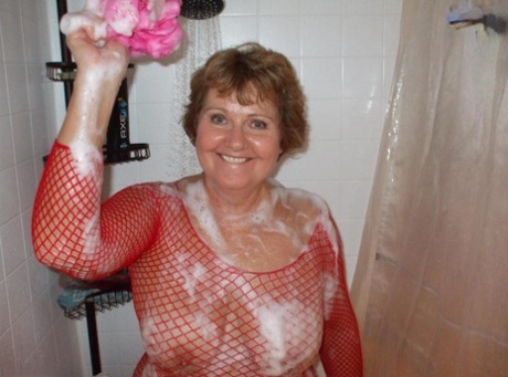 Older amateur Busty Bliss soaps up her boobs in a mesh dress