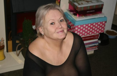 Old woman takes off her glasses before exposing her big ass and bald pussy