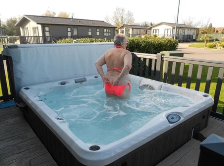 Fat nan bares her boobs while in a patio hot tub before getting naked on a bed