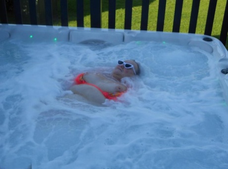 Fat nan bares her boobs while in a patio hot tub before getting naked on a bed