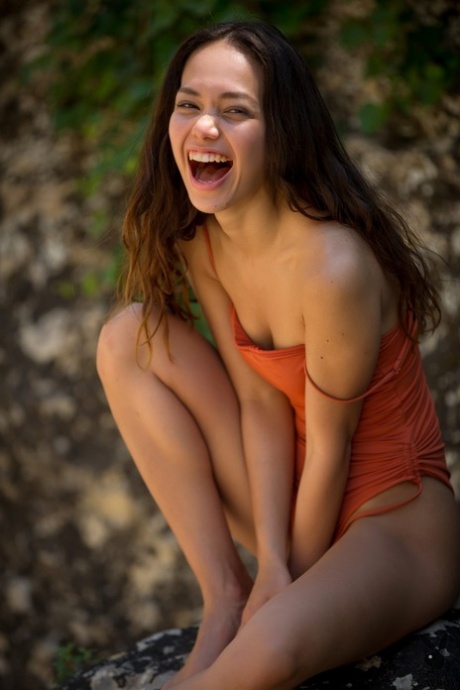 Petite brunette Kit Rysha frees her tiny tits from a swimsuit on a rocky shelf