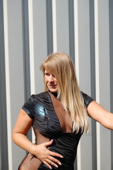 Mature blonde Sweet Susi doffs a leather dress to stand naked on a gangway