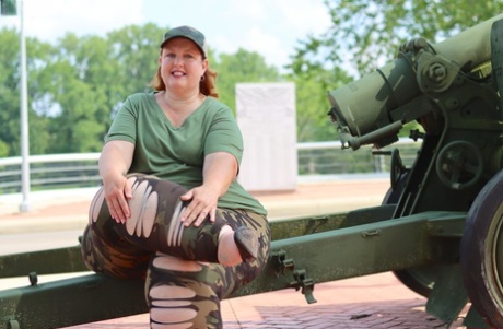 Obese amateur Goddess Pear models for a SFW shoot on an artillery gun in camo
