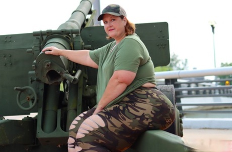 Obese amateur Goddess Pear models for a SFW shoot on an artillery gun in camo