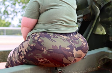 Obese amateur Goddess Pear models for a SFW shoot on an artillery gun in camo