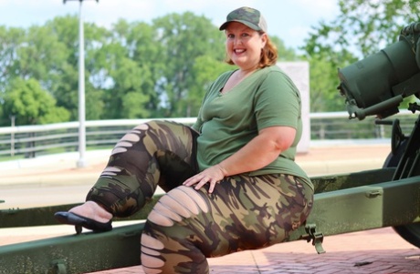 Obese amateur Goddess Pear models for a SFW shoot on an artillery gun in camo