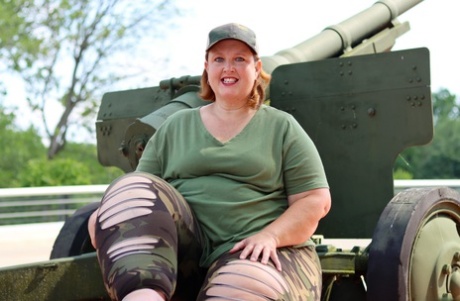 Obese amateur Goddess Pear models for a SFW shoot on an artillery gun in camo