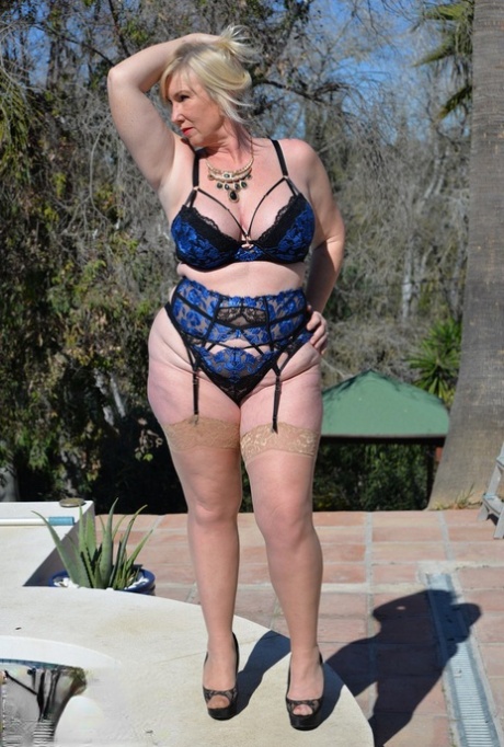 Overweight mature blonde Melody exposes her big natural tits near a pool