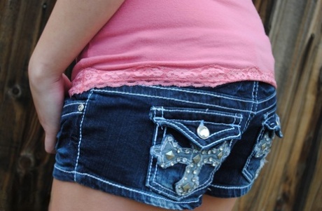Amateur girl Heavenly Smut poses near a backyard fence in denim shorts