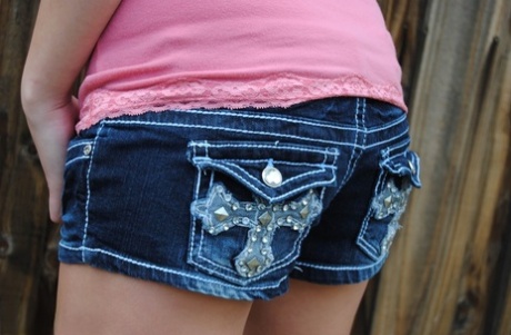 Amateur girl Heavenly Smut poses near a backyard fence in denim shorts
