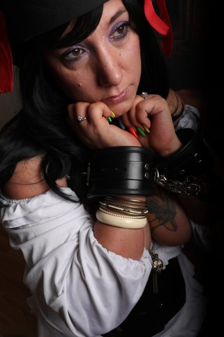 Dark-haired woman Sara Banks sports handcuffs while outfitted in pirate attire