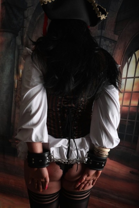 Dark-haired woman Sara Banks sports handcuffs while outfitted in pirate attire