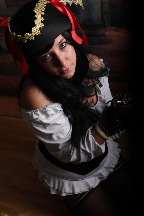 Dark-haired woman Sara Banks sports handcuffs while outfitted in pirate attire