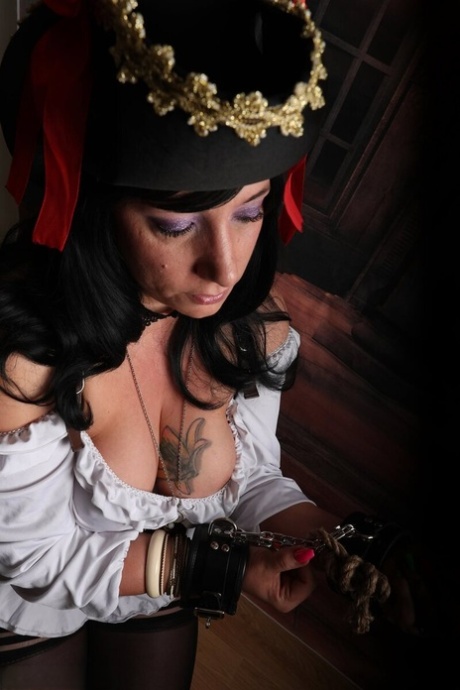 Dark-haired woman Sara Banks sports handcuffs while outfitted in pirate attire