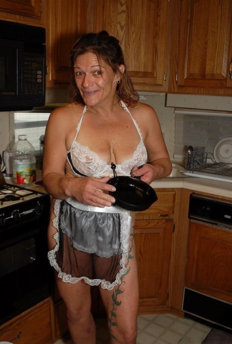 Granny Ivee showing off tattoos and shaved mature vagina in kitchen