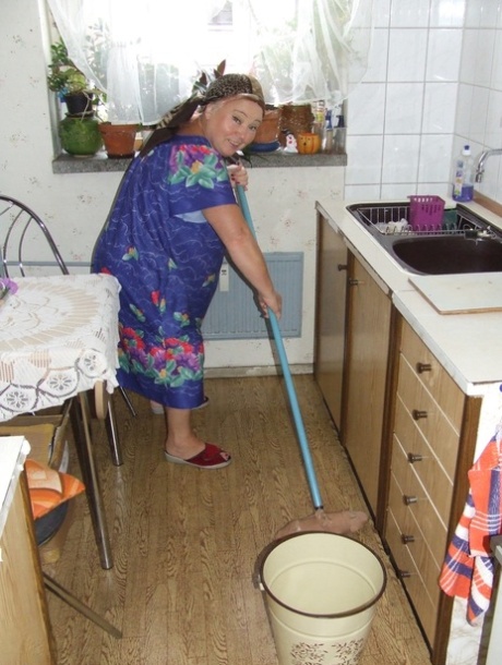 Fat granny Regina strips her clothes and poses while cleaning the kitchen