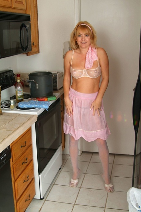 Redheaded housewife Trixie poses in her lingerie & masturbates while cooking